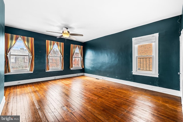 unfurnished room featuring a ceiling fan, hardwood / wood-style flooring, and baseboards