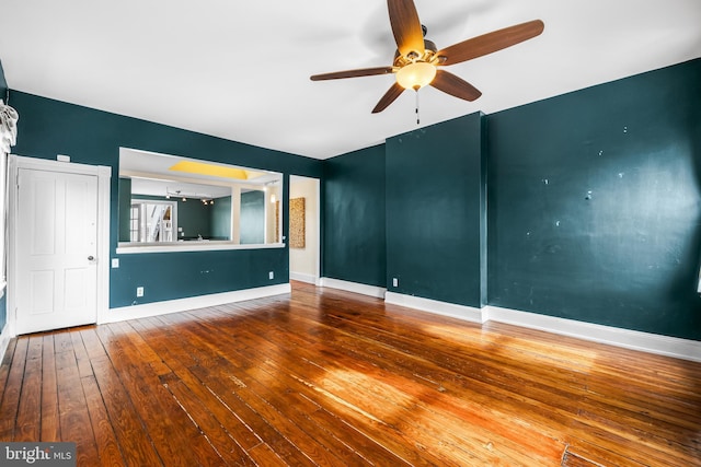 unfurnished living room featuring hardwood / wood-style flooring, baseboards, and a ceiling fan