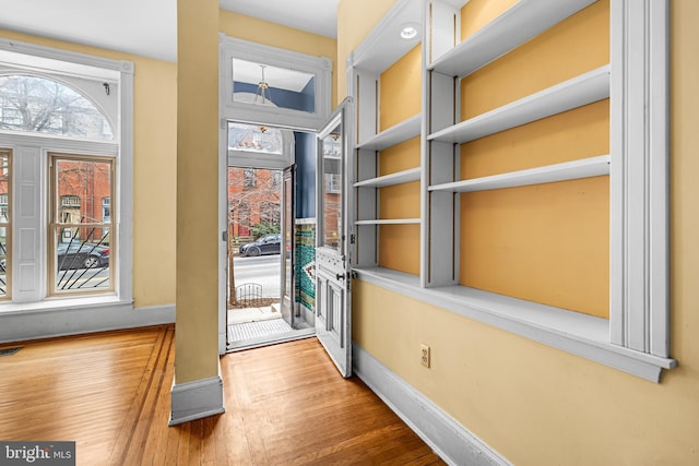 doorway to outside featuring built in features, wood finished floors, visible vents, and baseboards