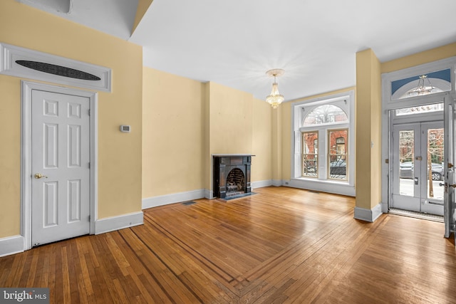 unfurnished living room with wood-type flooring, a fireplace with flush hearth, and baseboards