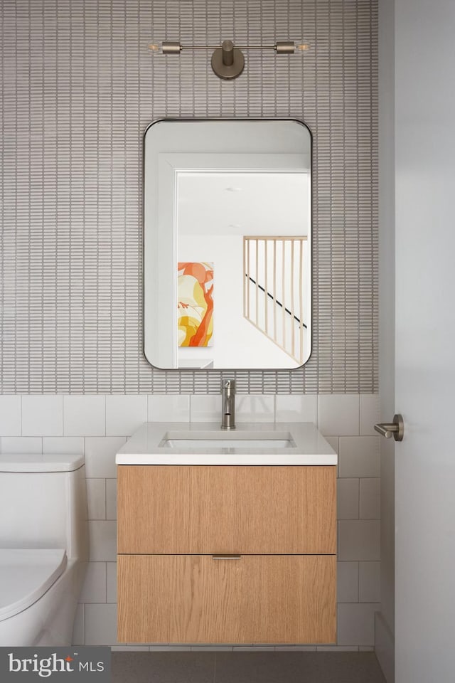 bathroom featuring tile walls, toilet, and vanity