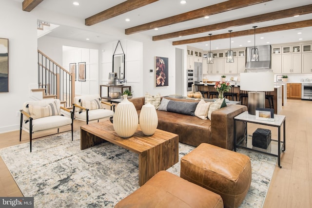 living room with light hardwood / wood-style floors, beamed ceiling, and beverage cooler