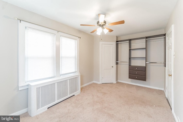 unfurnished bedroom with ceiling fan, light colored carpet, and radiator heating unit