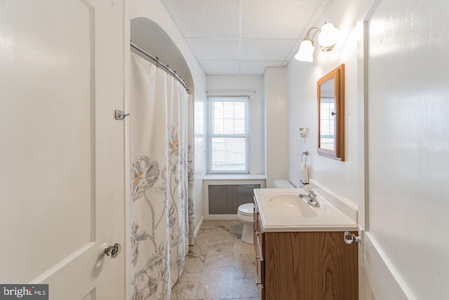 bathroom with a drop ceiling, toilet, and vanity