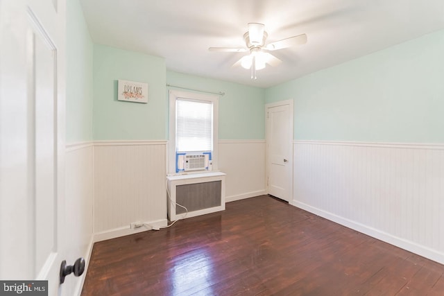 empty room featuring ceiling fan, dark wood-type flooring, cooling unit, and radiator