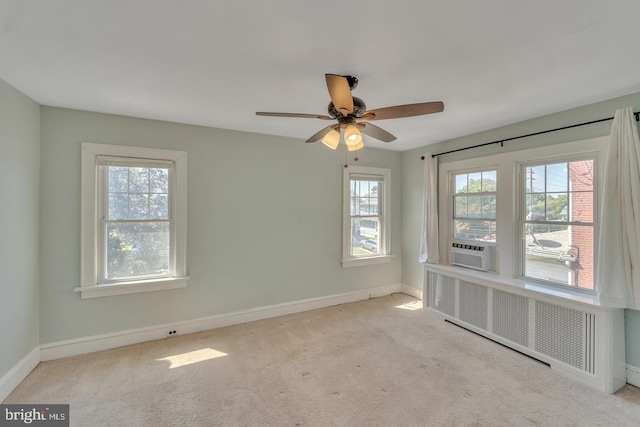 carpeted empty room featuring ceiling fan, radiator heating unit, and a healthy amount of sunlight