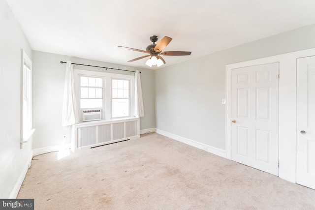 empty room featuring light colored carpet, radiator, cooling unit, and ceiling fan