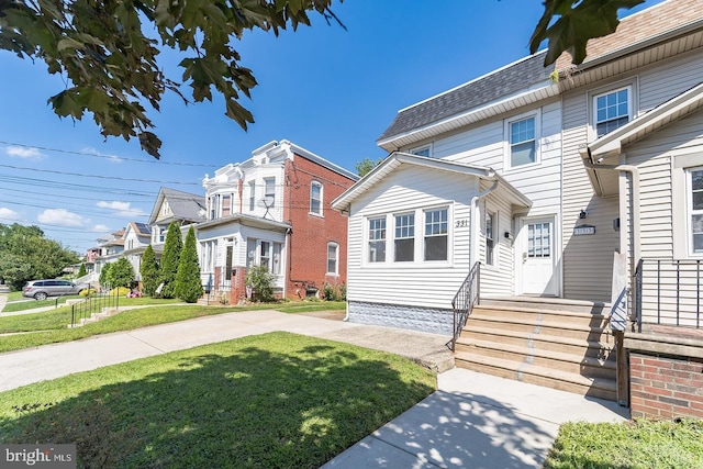 view of front of property with a front yard, roof with shingles, and entry steps