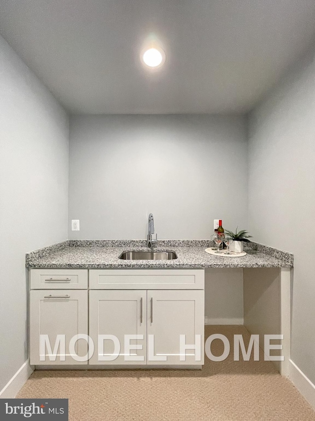 interior space featuring sink, light colored carpet, white cabinets, and light stone countertops