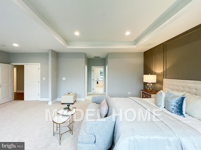 bedroom with light colored carpet and a tray ceiling