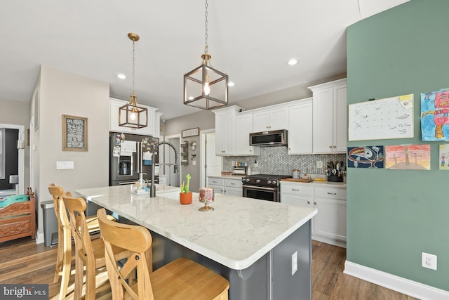 kitchen featuring pendant lighting, white cabinetry, stainless steel appliances, and a kitchen island with sink