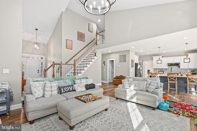 living room with a towering ceiling, hardwood / wood-style floors, and a chandelier