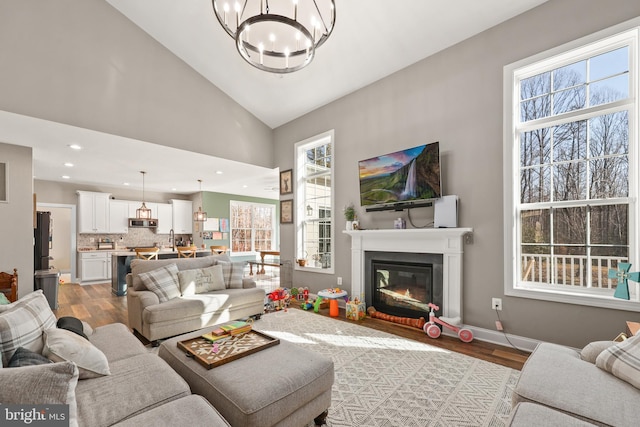 living room with lofted ceiling, sink, hardwood / wood-style flooring, and an inviting chandelier