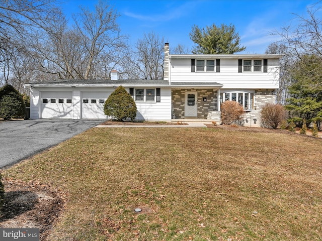 view of front of house with a front yard, driveway, a chimney, and an attached garage