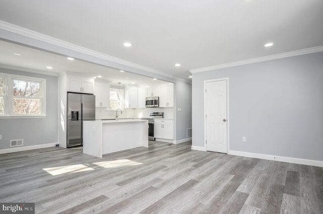 kitchen featuring crown molding, white cabinetry, a center island, and appliances with stainless steel finishes