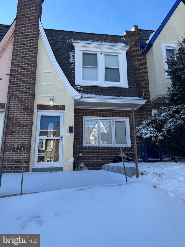 view of front of home with brick siding and roof with shingles