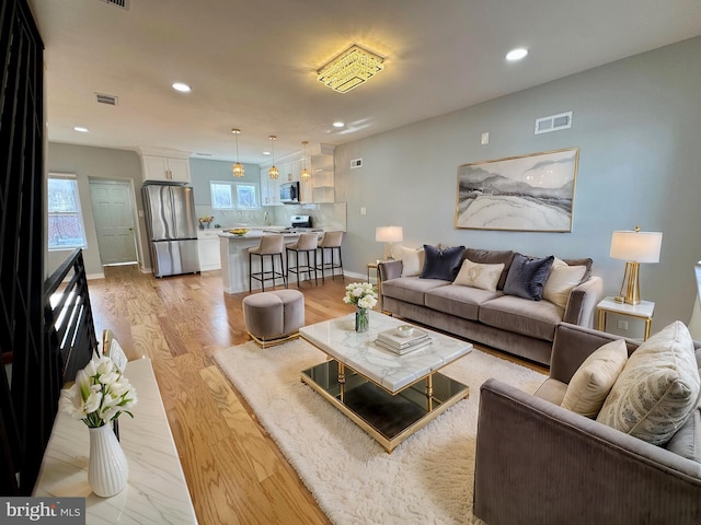 living room featuring visible vents, light wood-style flooring, and recessed lighting