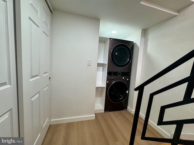 clothes washing area featuring stacked washer and dryer and light hardwood / wood-style floors