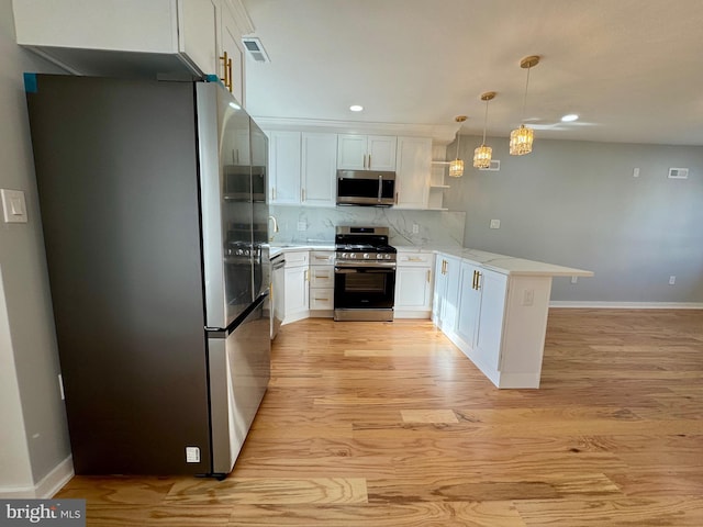 kitchen featuring appliances with stainless steel finishes, white cabinets, backsplash, hanging light fixtures, and kitchen peninsula