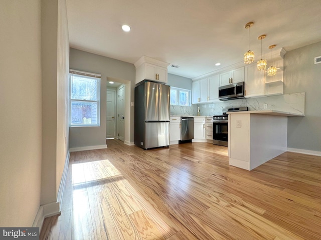 kitchen featuring white cabinetry, hanging light fixtures, backsplash, stainless steel appliances, and kitchen peninsula