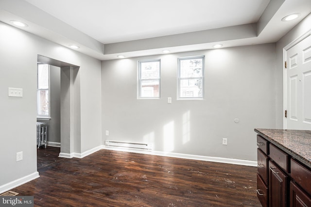 interior space with a baseboard heating unit and dark hardwood / wood-style floors