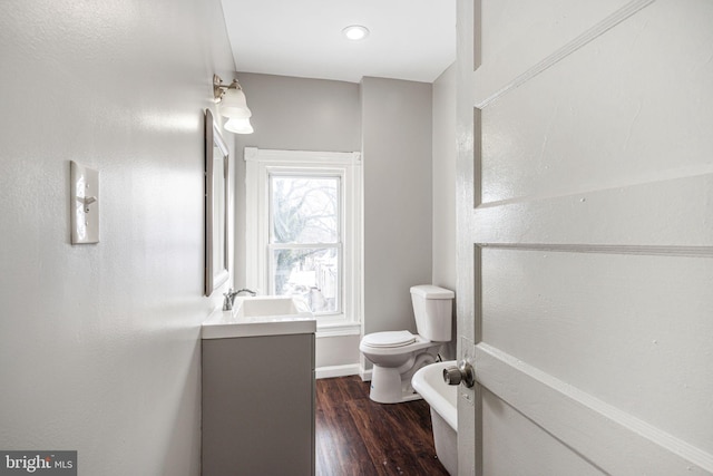 bathroom featuring wood-type flooring, toilet, vanity, and a healthy amount of sunlight