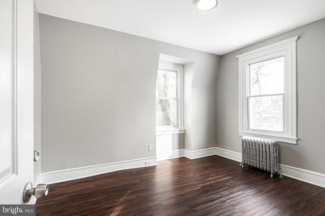 empty room featuring radiator heating unit and dark hardwood / wood-style flooring