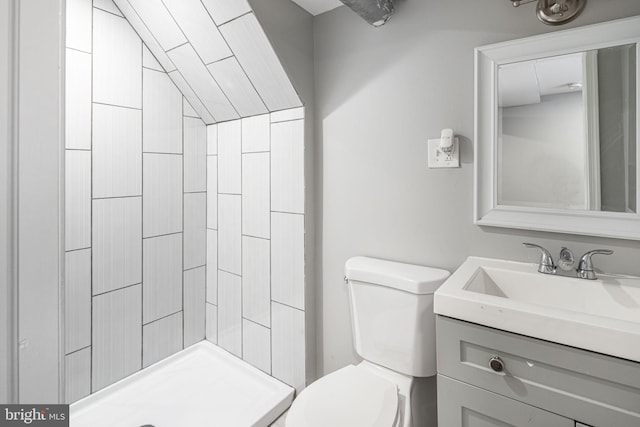 bathroom with tiled shower, toilet, and vanity