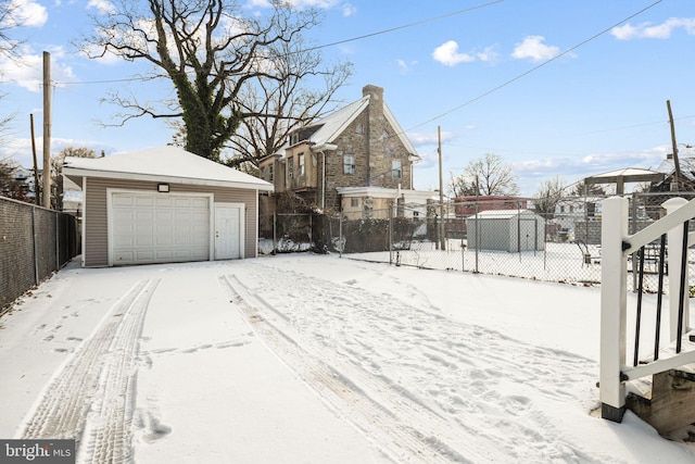 yard covered in snow with a garage and an outdoor structure