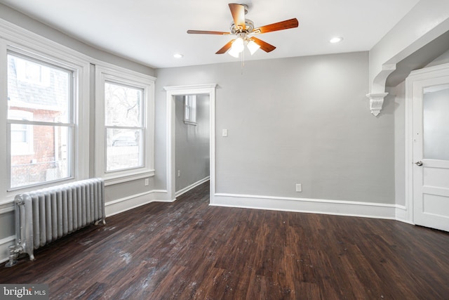 unfurnished room with dark hardwood / wood-style floors, radiator, and ceiling fan