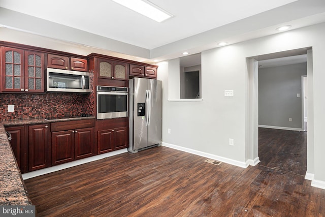 kitchen with decorative backsplash, dark hardwood / wood-style floors, dark stone counters, and stainless steel appliances