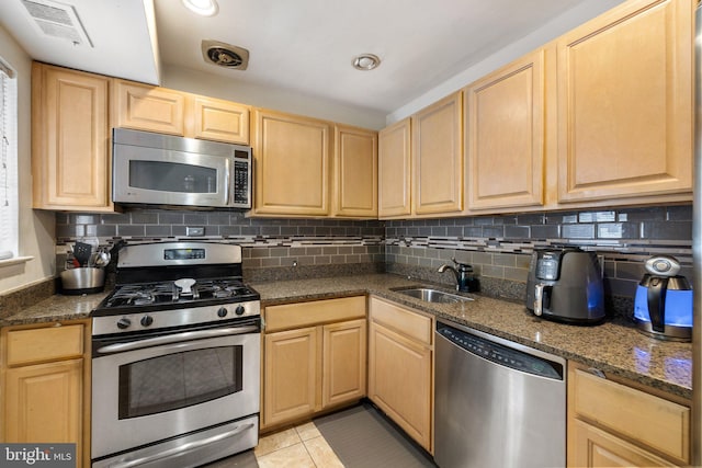 kitchen featuring sink, decorative backsplash, light tile patterned floors, and stainless steel appliances