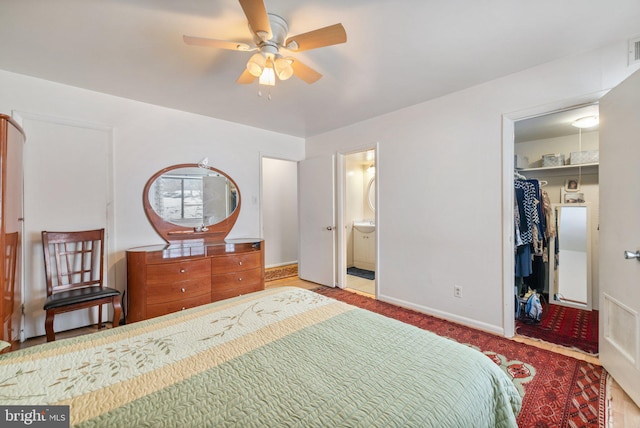 bedroom with a spacious closet, connected bathroom, a closet, and ceiling fan