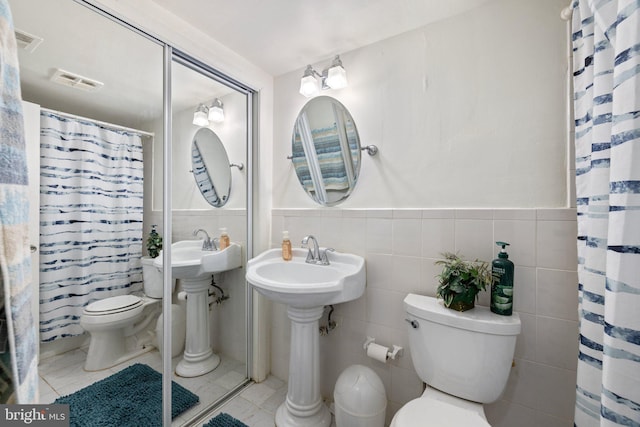 bathroom with tile patterned floors, tile walls, toilet, and walk in shower