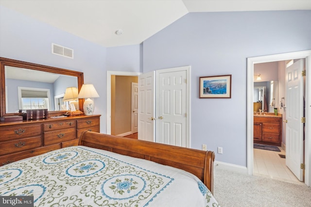 carpeted bedroom featuring vaulted ceiling, ensuite bath, and a closet