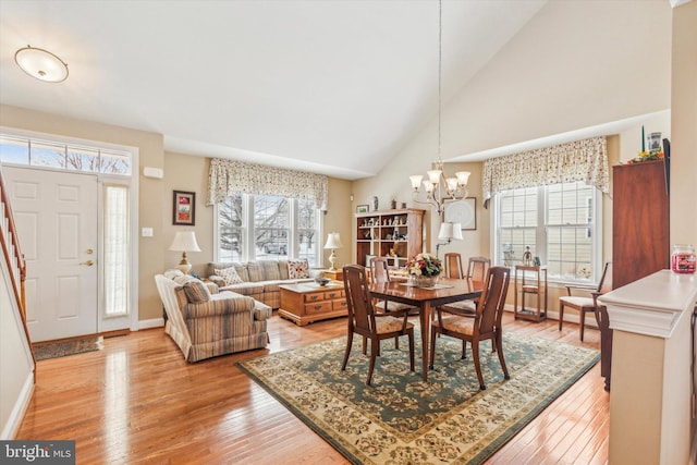 dining room featuring a chandelier, high vaulted ceiling, and light wood-type flooring