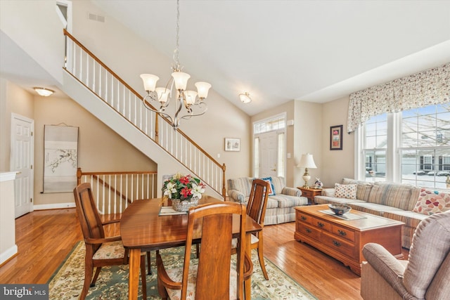 dining room featuring hardwood / wood-style flooring, vaulted ceiling, and a notable chandelier