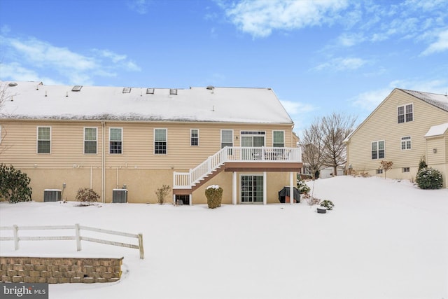 snow covered rear of property featuring a deck and central AC unit