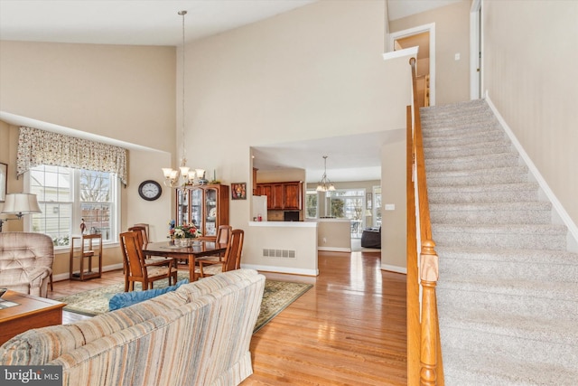 living room featuring a chandelier, light wood-type flooring, a high ceiling, and a wealth of natural light