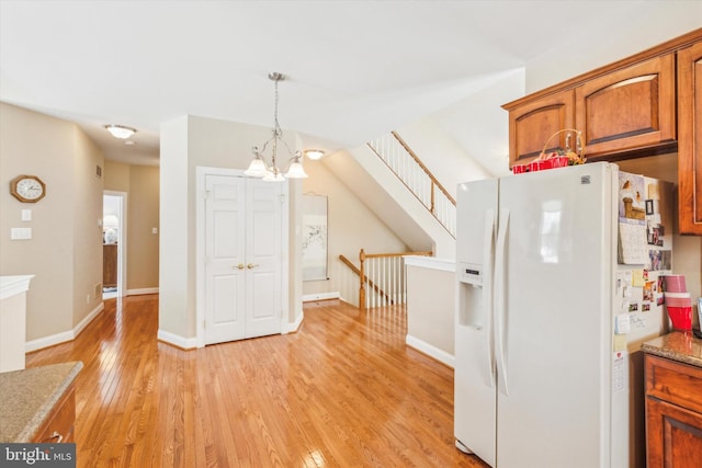 kitchen with hanging light fixtures, white refrigerator with ice dispenser, light hardwood / wood-style floors, and a chandelier