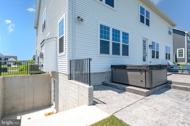 view of side of property featuring a patio area and a hot tub