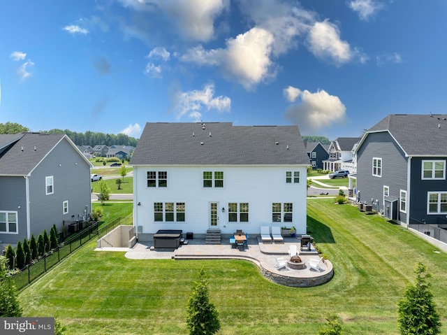 rear view of property with a yard, a hot tub, a fire pit, and a patio area