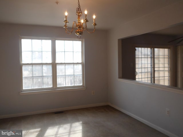 unfurnished room featuring carpet and a notable chandelier