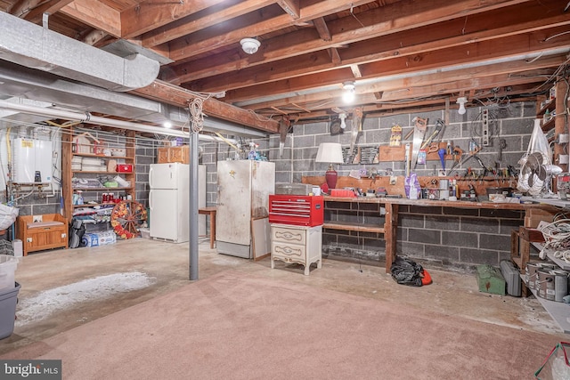 basement featuring white fridge, refrigerator, and a workshop area