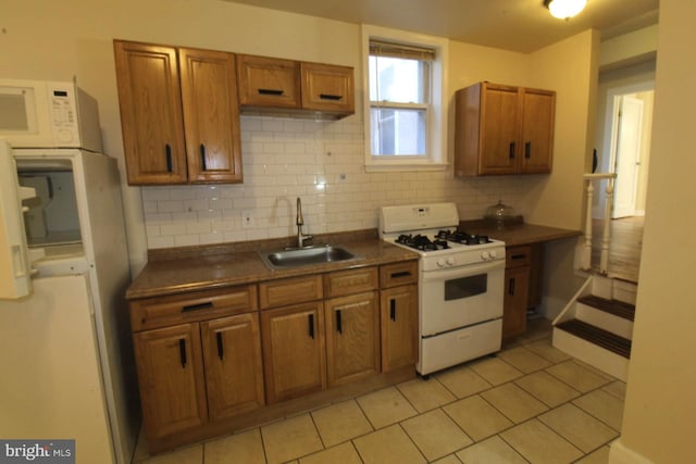 kitchen with sink, light tile patterned floors, white appliances, and decorative backsplash