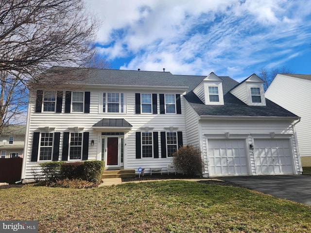 colonial inspired home featuring a front lawn, an attached garage, driveway, and a shingled roof