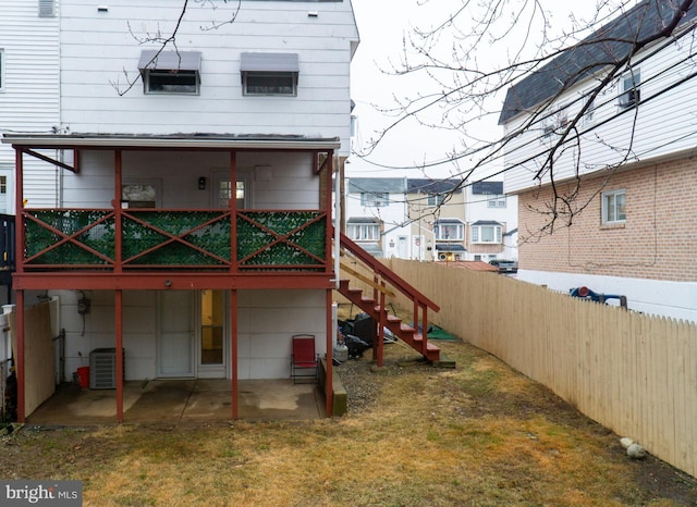 rear view of house with central AC unit, a patio area, and a lawn