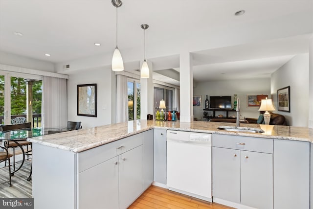 kitchen with light stone countertops, dishwasher, sink, and kitchen peninsula