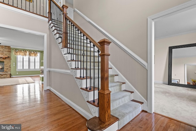 staircase featuring hardwood / wood-style flooring and a stone fireplace