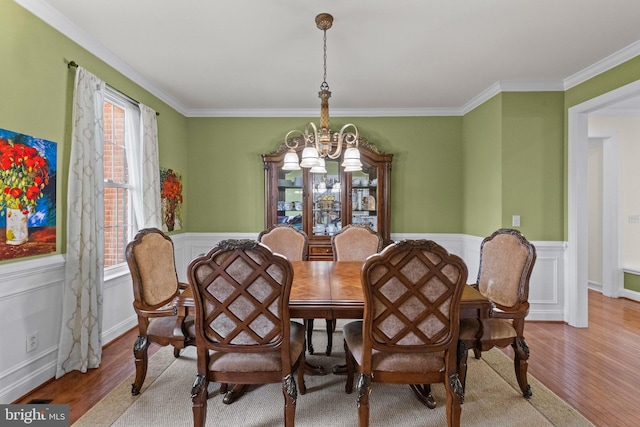 dining space with crown molding, light hardwood / wood-style flooring, and a chandelier